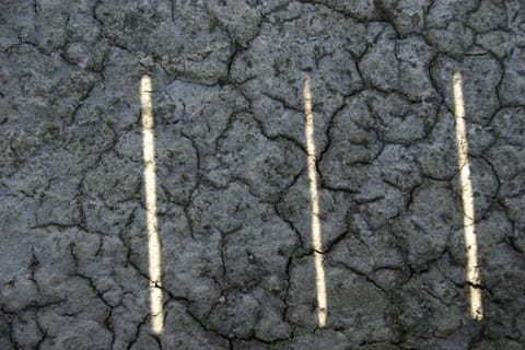 Three slivers of light peek through the boardwalk onto the crusted and cracked salt mud.