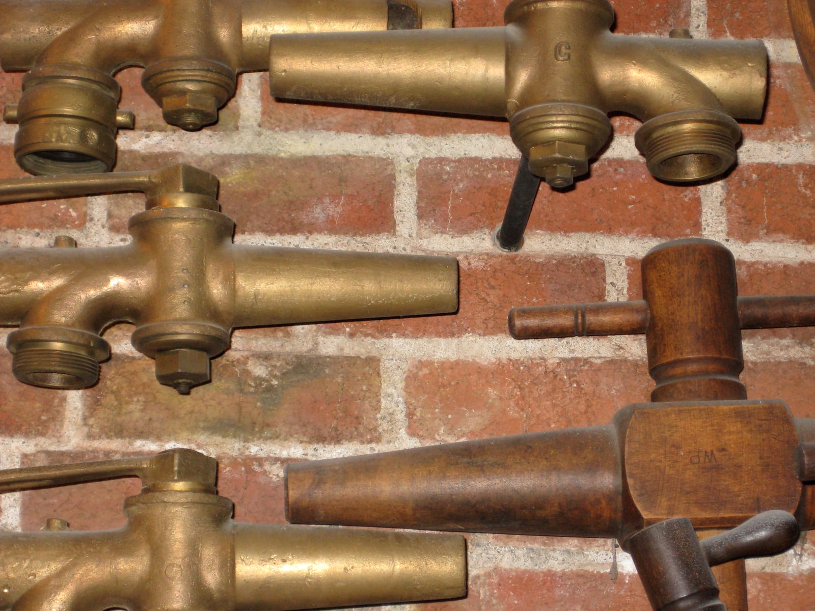 Spigots against a red brick wall.